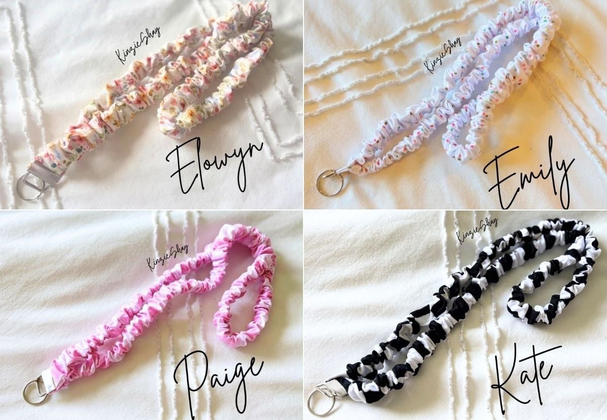 Set of four personalized fabric keychains with ruffled design in pink, black, white, and multicolor, each with a metal keyring, displayed on a white fabric background.