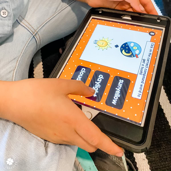 The image shows a child using a tablet with digital task cards focused on grammar, specifically about the sun and moon, for 2nd and 3rd grade students.