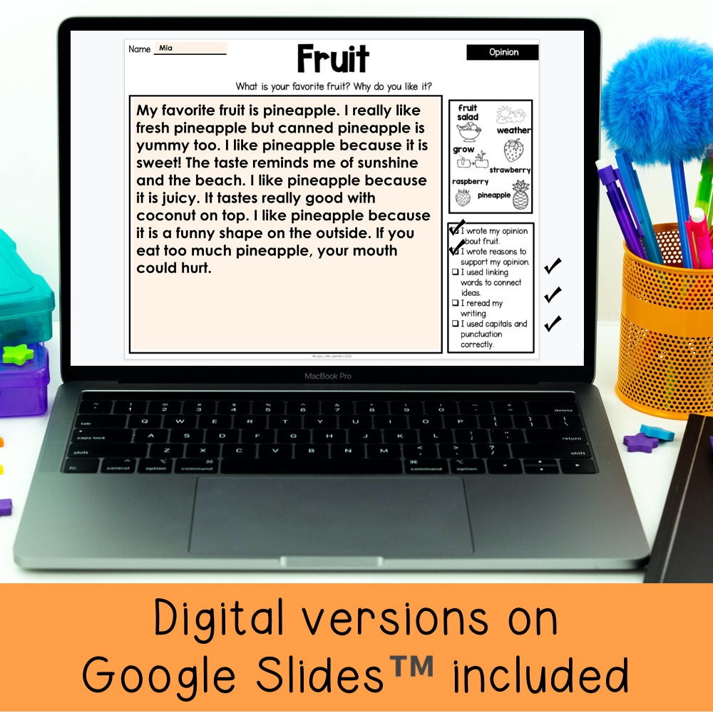 A colorful digital classroom scene featuring a laptop displaying a writing prompt about fruit, with a bright orange banner at the bottom promoting digital versions on Google Slides for 1st and 2nd gr.