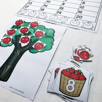 A colorful educational activity for 1st grade students featuring a paper tree with apple cutouts, number cards, and a math counting game, perfect for September math centers and activities.