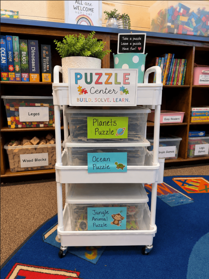 Educational puzzle storage cart with labeled boxes for planets, ocean, jungle, and animal puzzles in a classroom setting, promoting learning and organization.